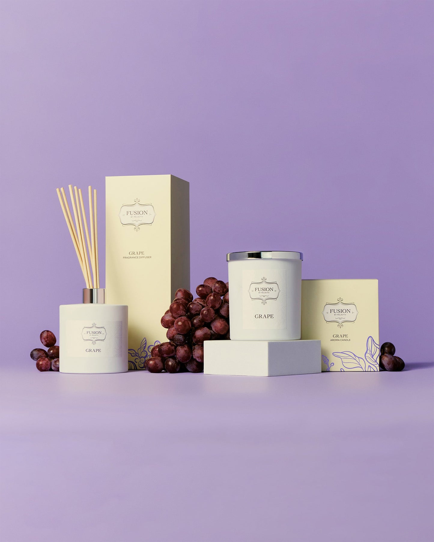 A group photo featuring a white glass jar candle and matching white glass jar diffuser surrounded by decorative dark purple grapes against a vibrant purple background.