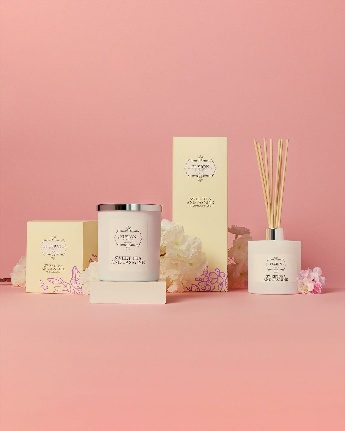 Elegant display of a Sweet Pea and Jasmine candle and diffuser set against a soft pink background, accented with white flowers, conveying calm and luxury.
