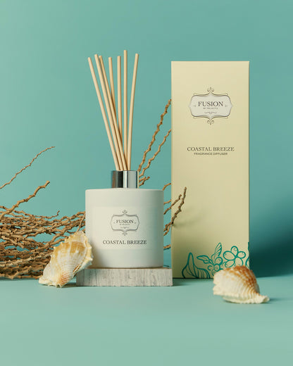 A reed diffuser is positioned next to a box adorned with a sea shell, enhancing a serene and beachy atmosphere.