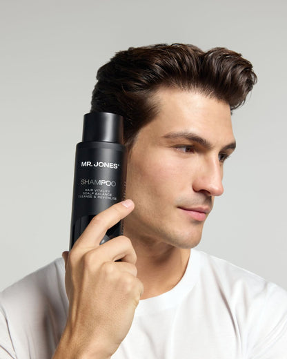 Man holding a bottle of 'Mr. Jones Shampoo' with a gray background